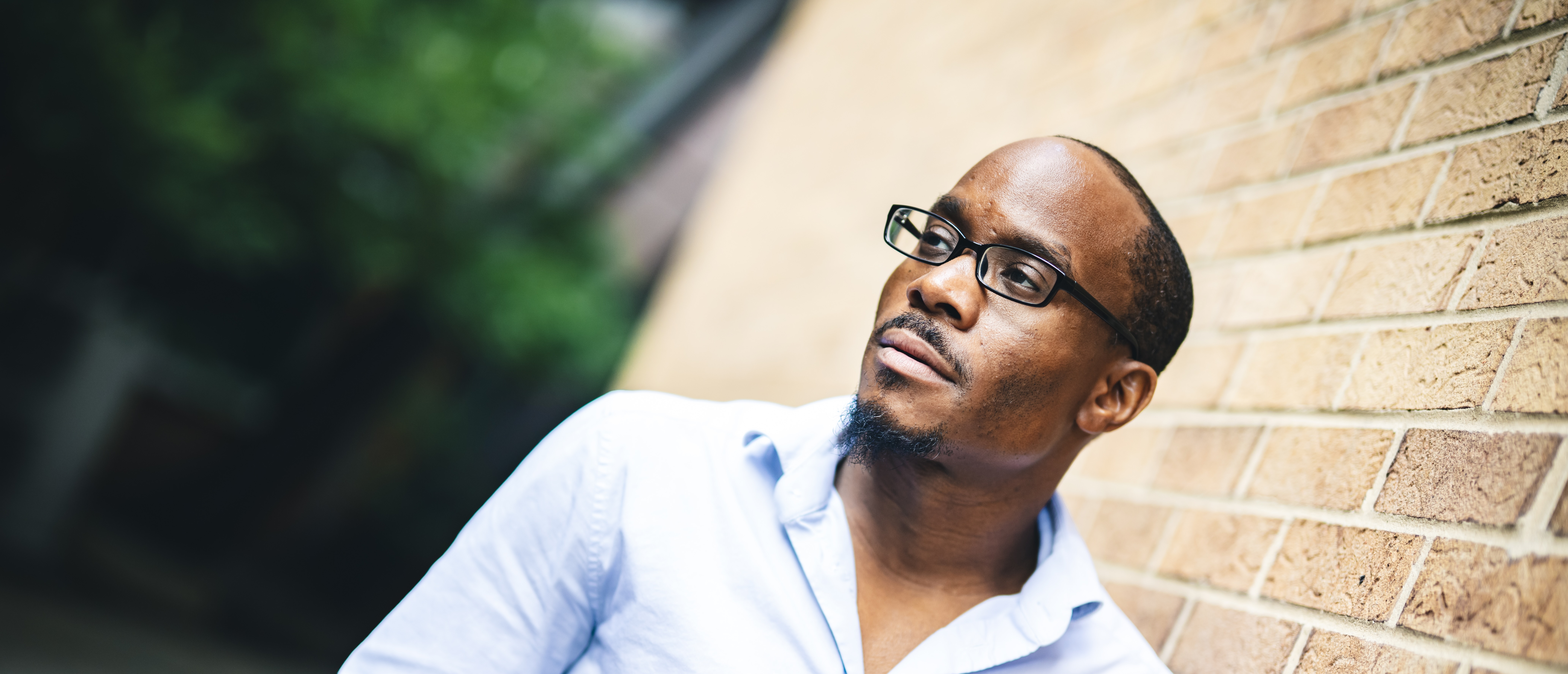Joseph Williams poses for a photo leaning against a brick wall.