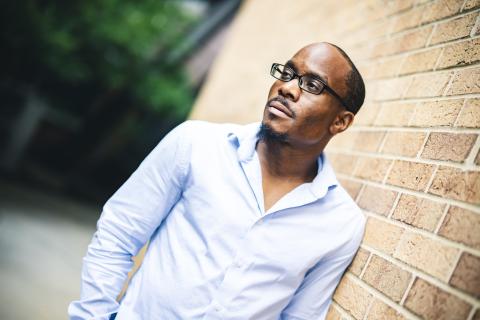 Joseph Williams poses for a photo leaning against a brick wall.